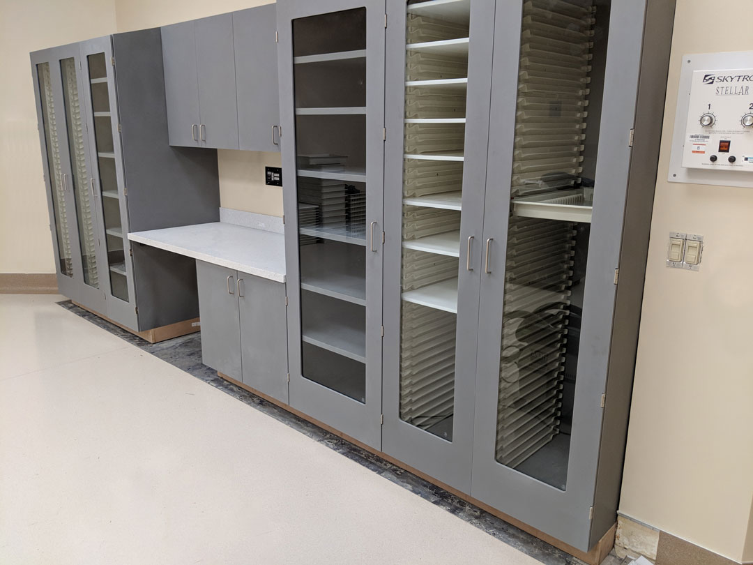 Shield Acrylic solid surface medical storage cabinets with sloped tops in grey in operating room with fixed and high density storage shelving options