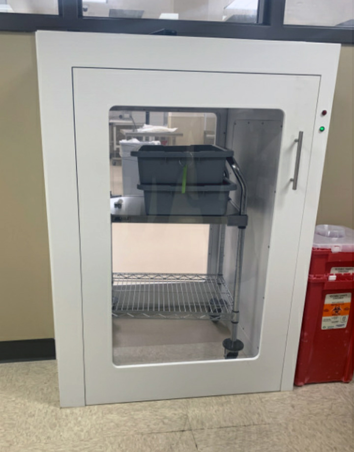 Shield Casework Healthcare acrylic solid surface floor-cart pass-through cabinet is USP 797 and 800 compliant and shown in pharmacy from Ante room