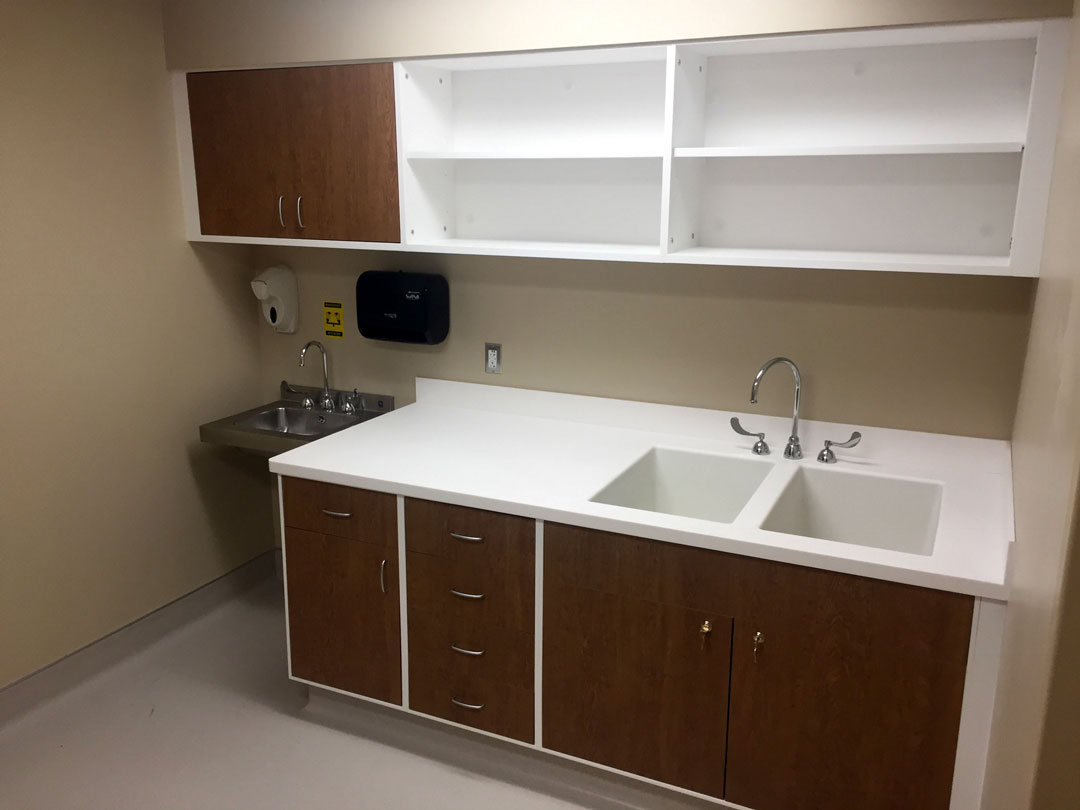 Shield Casework’s hybrid acrylic solid surface wedge line of casework in operating control room with oak laminated door faces and white acrylic solid surface finishes